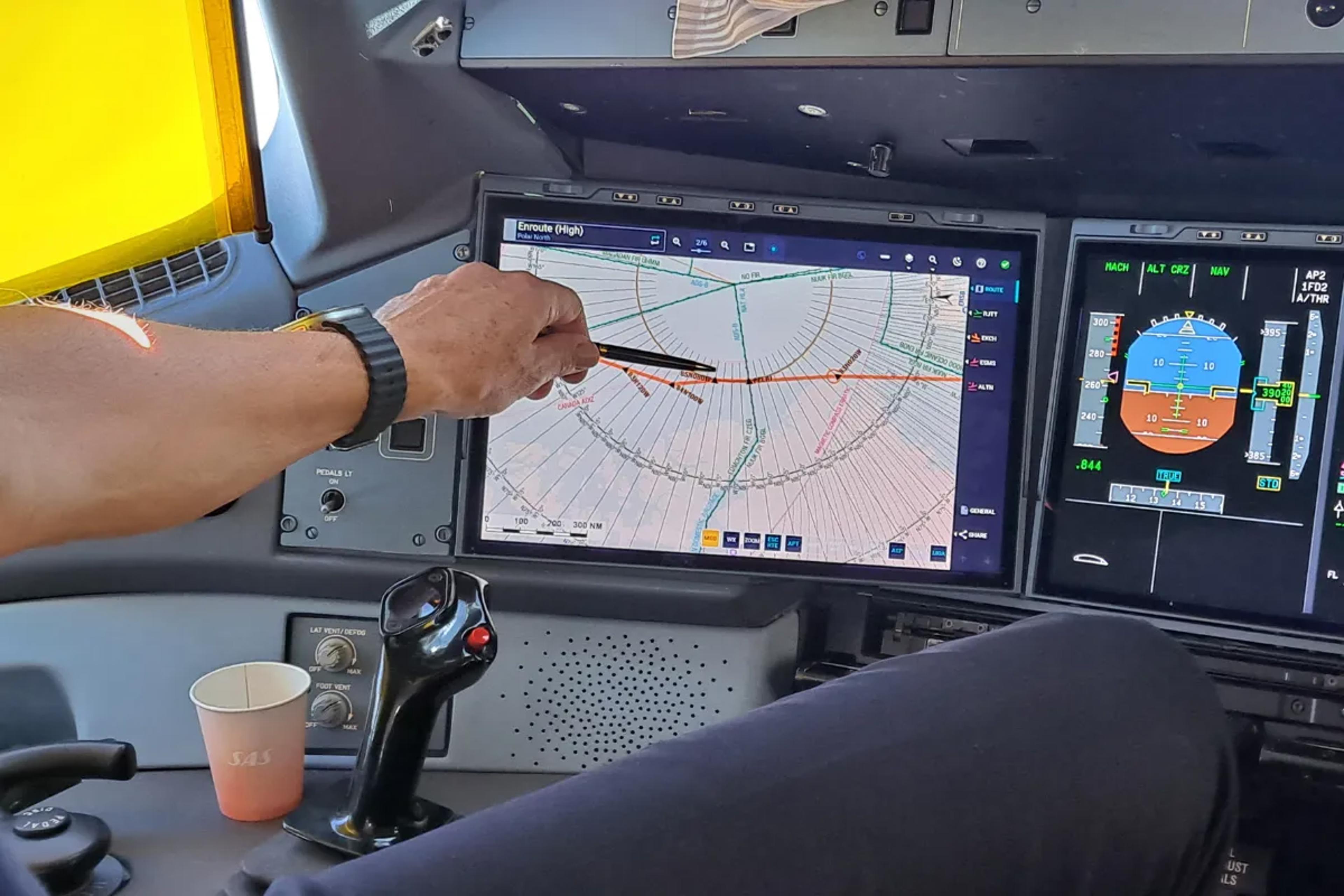 Pilot peger på et kort i cockpittet på SAS' Airbus A350.