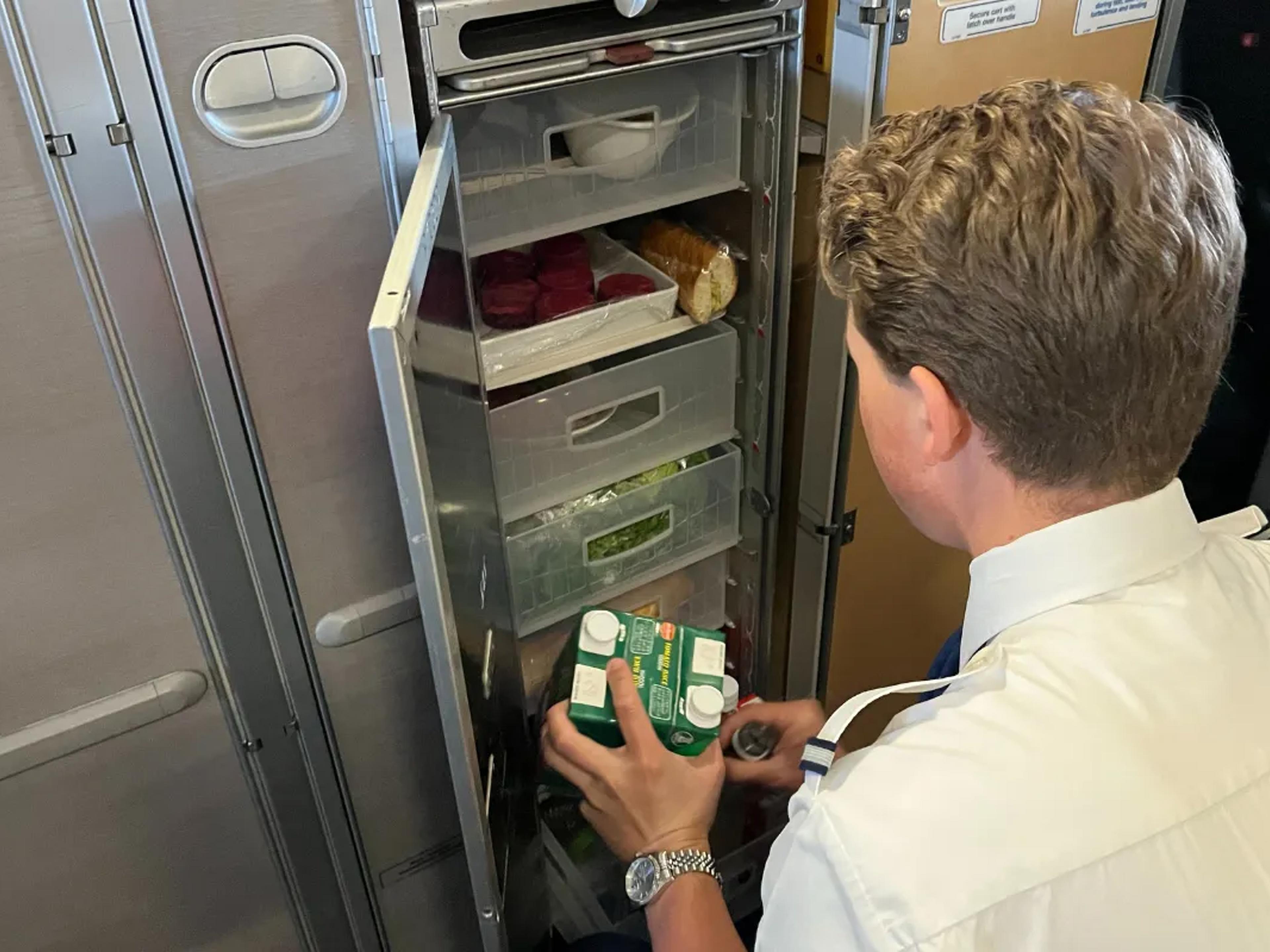 Air steward fylder drikkevarer på trolley.